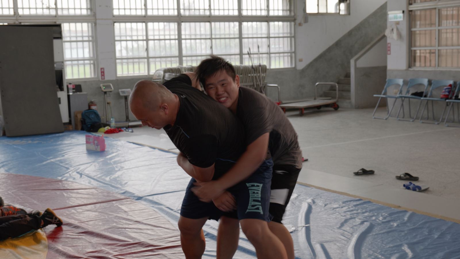 逆轉ㄟ阿坤 教練和少年選手在體育館墊上練習角力的抱摔動作