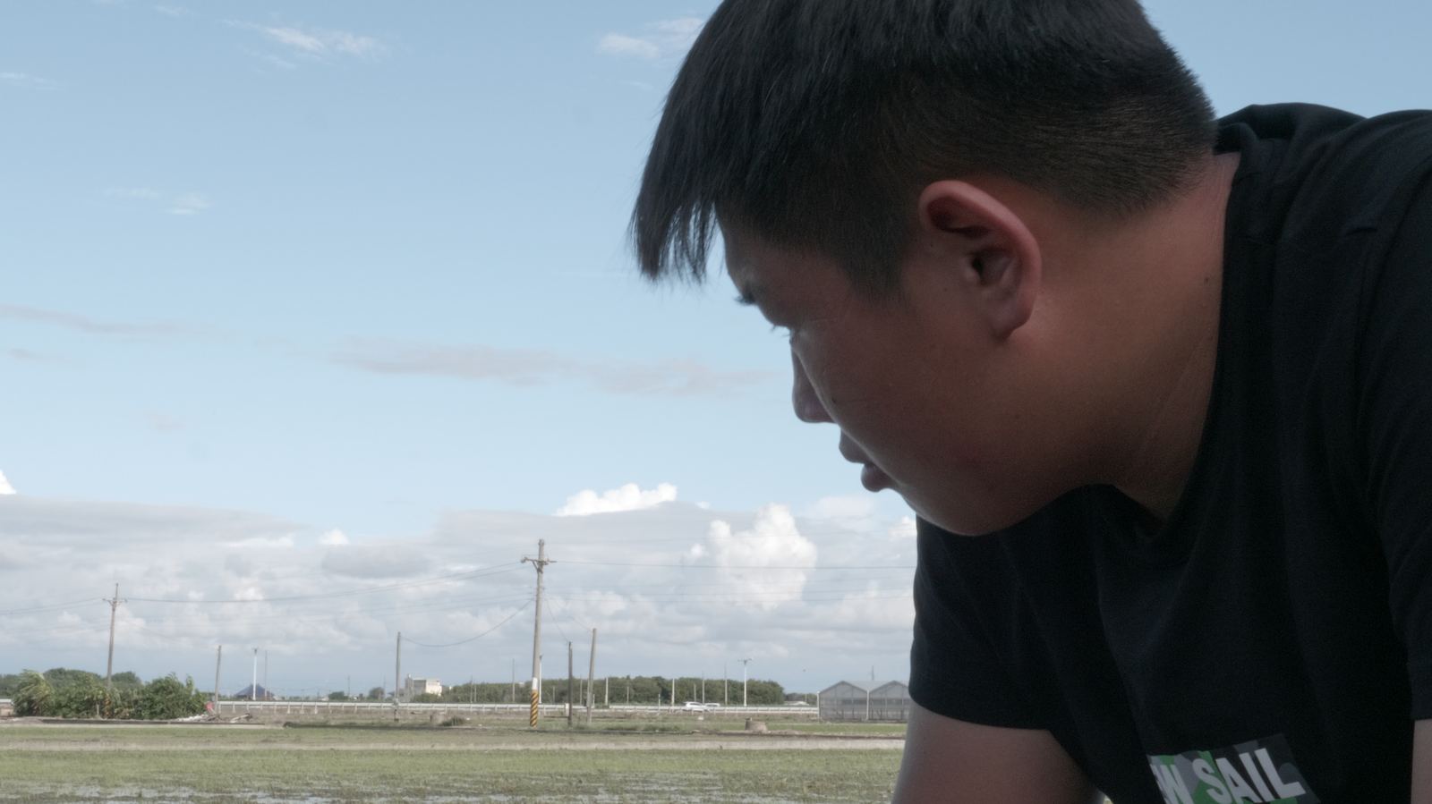 逆轉ㄟ阿坤 少年低頭俯身備戰，背後是農田與藍天白雲