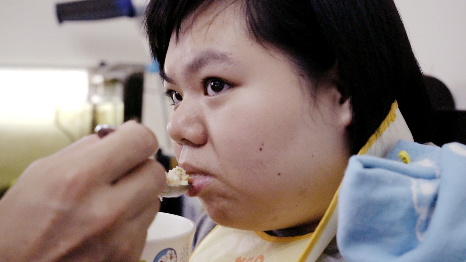 沈默天使 爸爸用湯匙餵食坐在餐椅上的女兒