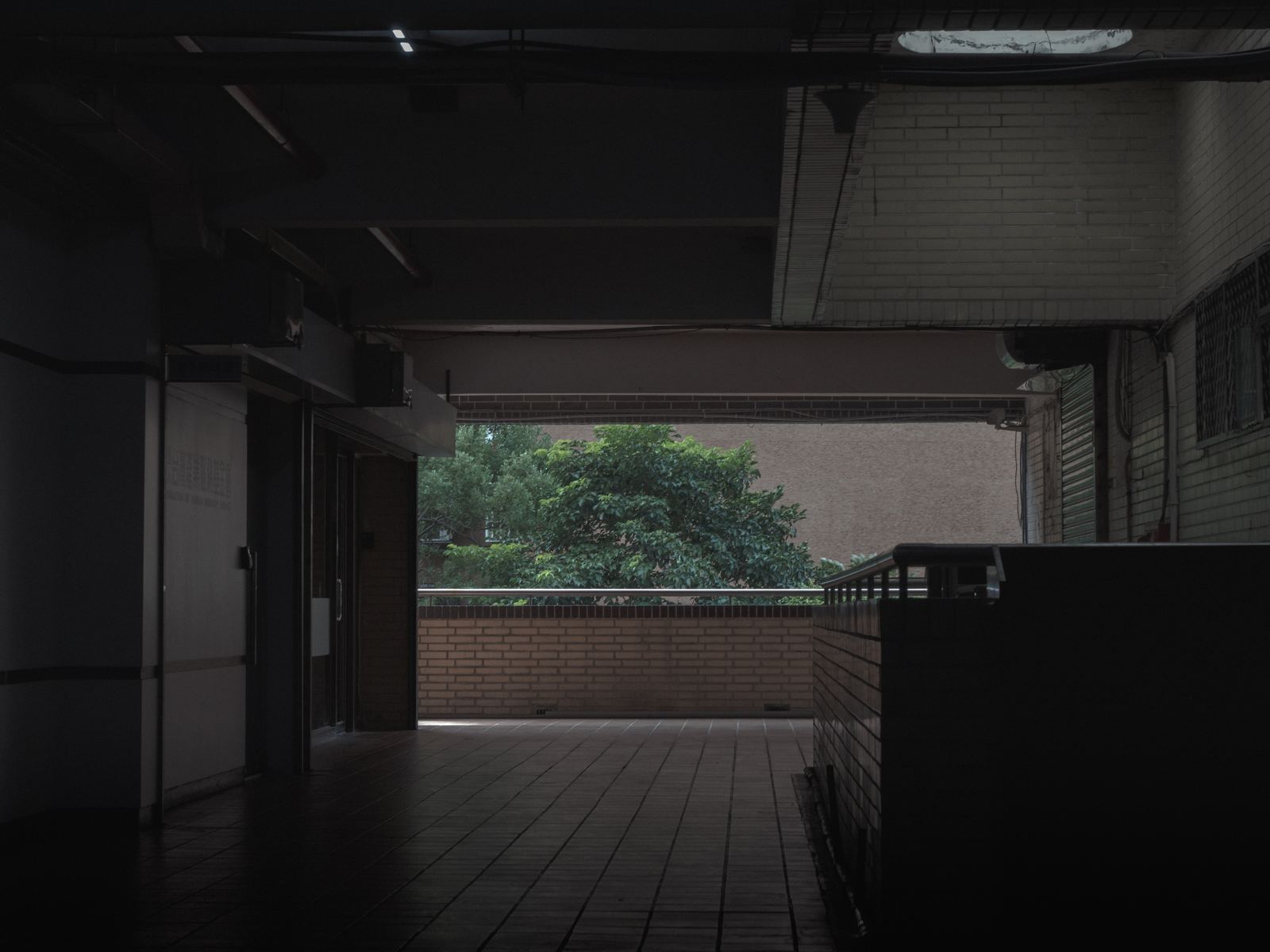 幕 空無一人的社區騎樓，遠處綠樹在光裡