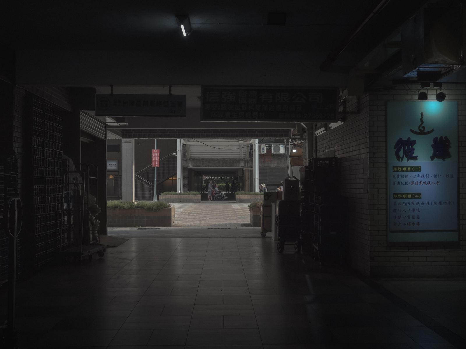 幕 昏暗的商店街，藍色招牌燈箱在右側發亮