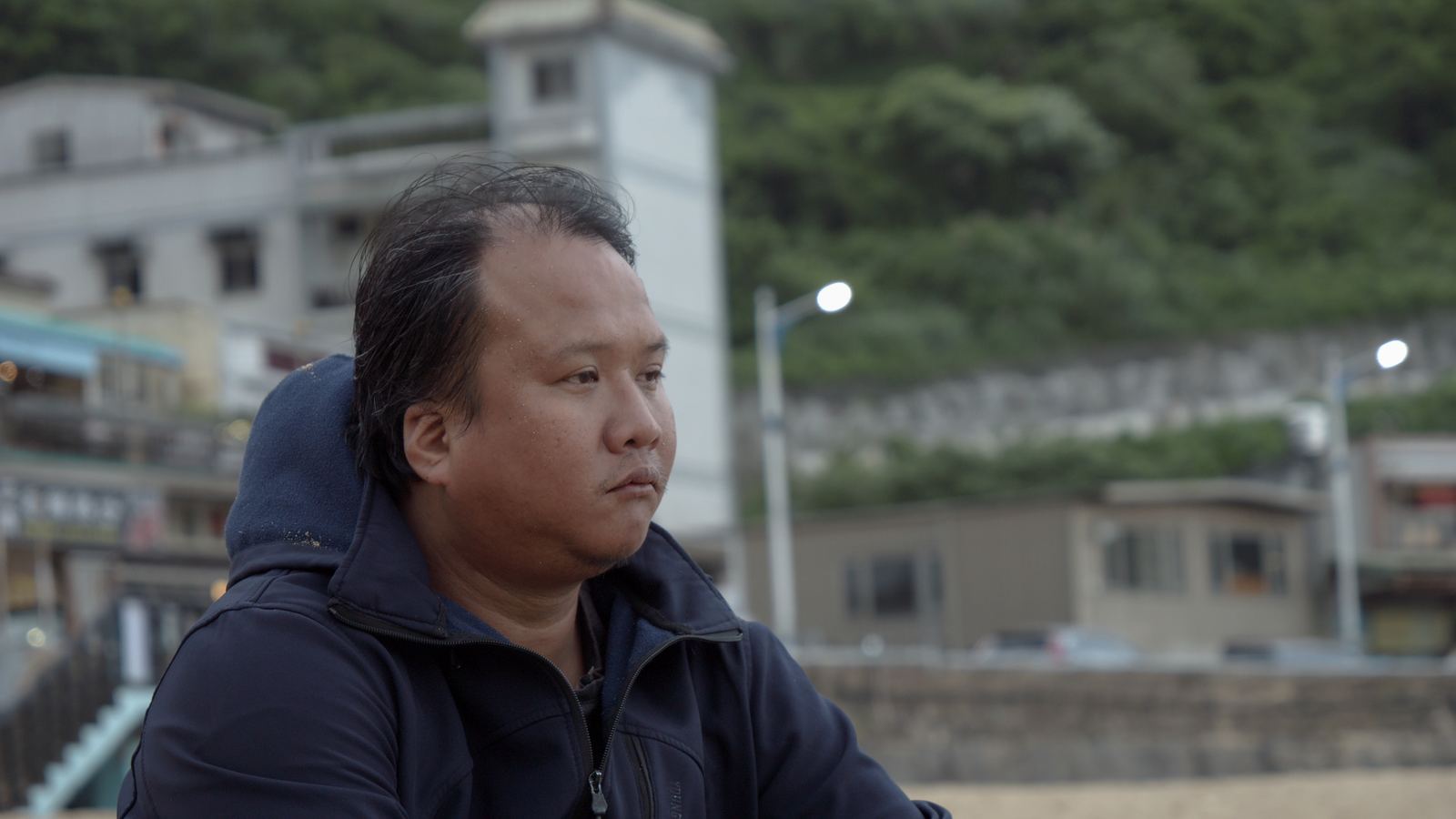 尋找棲所 男子坐在海堤邊側頭望向遠方