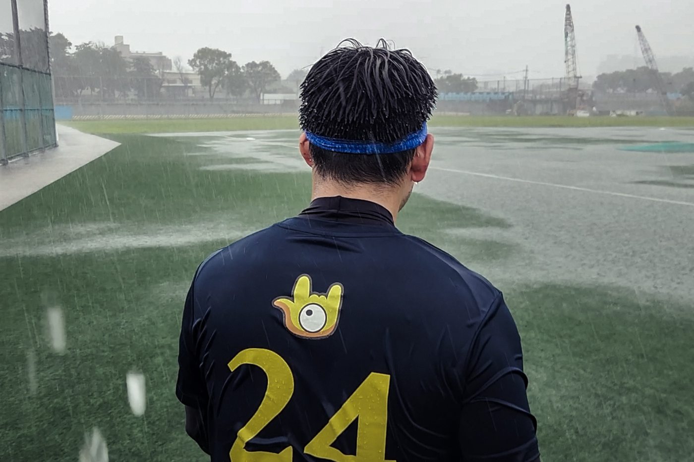 我是聾人 我的母語是手語 大雨中球員背對鏡頭走向球場，背號二十四