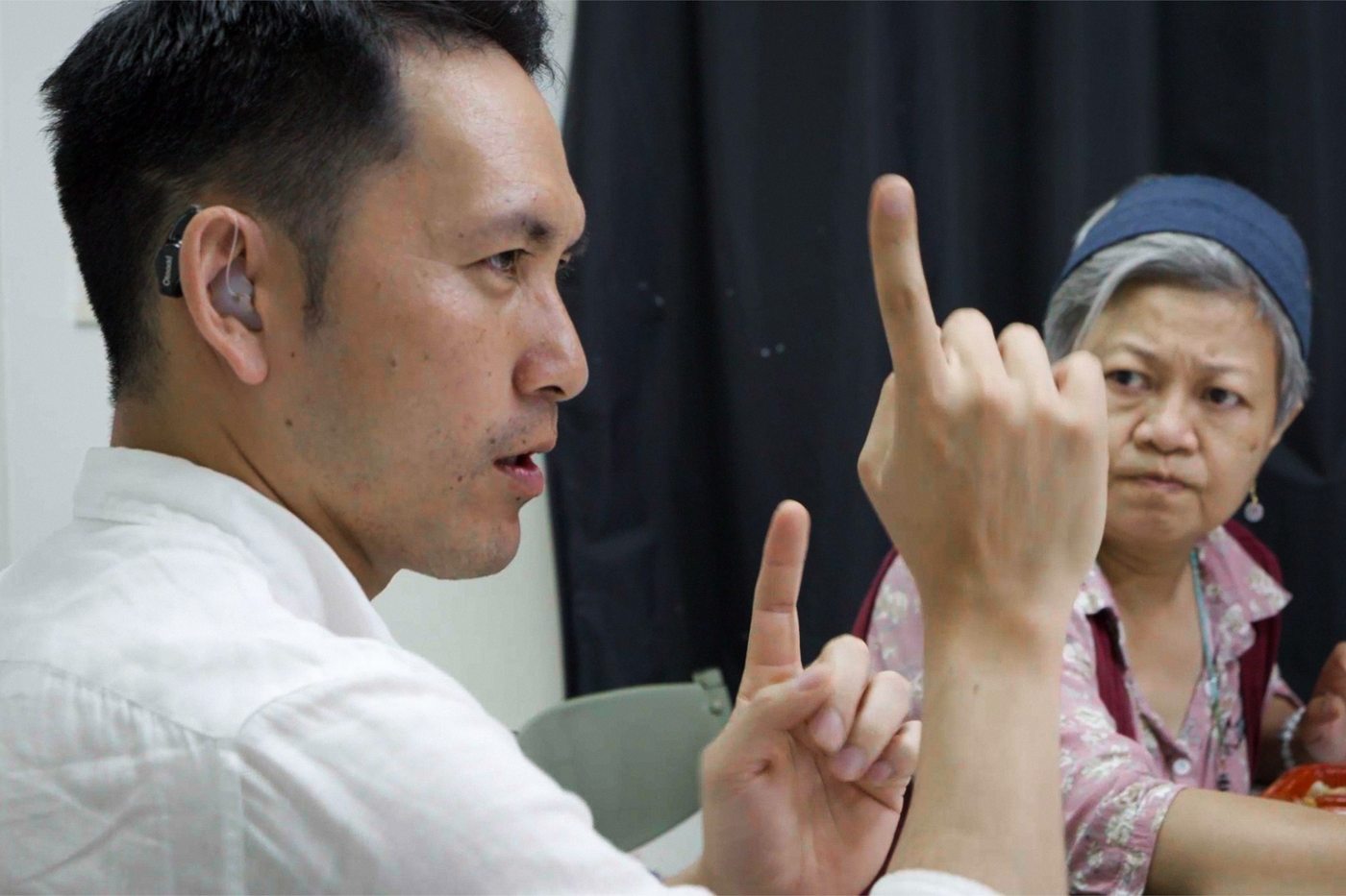 我是聾人 我的母語是手語 男子側臉比著手語