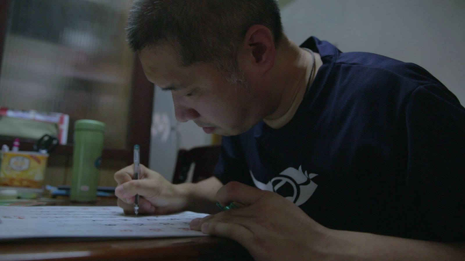 溫度-輻射 男子伏在桌前握筆專注書寫