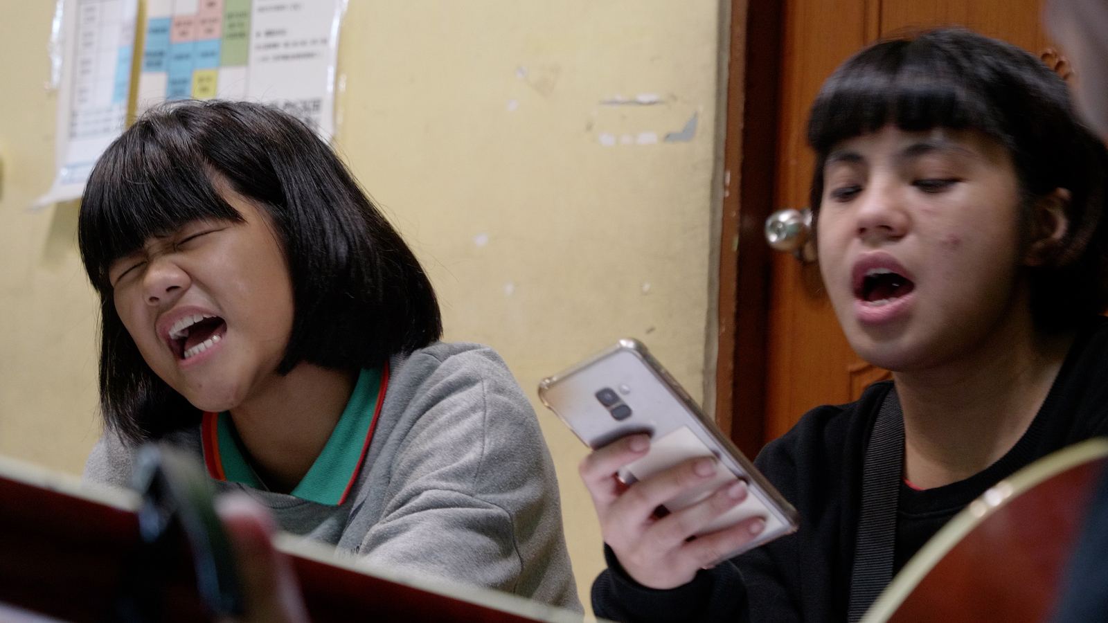 看見WAWA森林 兩名女孩看著手機螢幕一起放聲唱歌