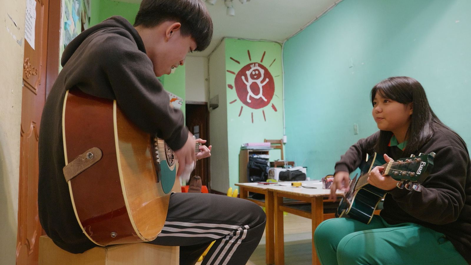看見WAWA森林 少年抱著木吉他練習，另一名女孩在對面撥弦