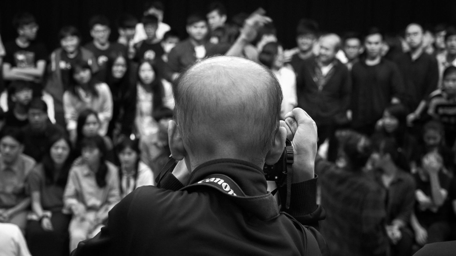 雲 少年攝影師背對鏡頭為一大群人拍攝團體照